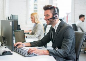 A customer service representative man wearing headphone attending the call with a smile on his face