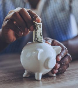 A black man saving money in a piggy bank